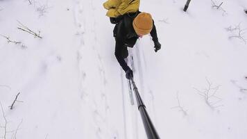 An adventurous person in black with a bright yellow backpack navigates a snowy landscape, surrounded by tall trees, effortlessly capturing peaceful moments in the crisp air video