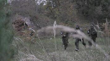 hree men of paintball players run in the forest in slow motion video