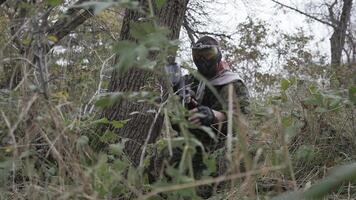 Paintball player crawling on plastunno slow-motion shooting video