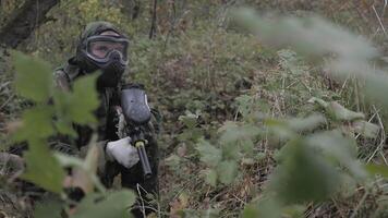 Paintball player in grass shoots in slow motion video