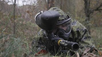 Paintball player in grass aiming in slow motion video