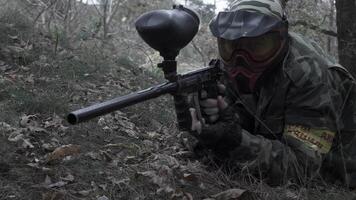 A man lying on the grass shooting from a paintball in slow motion video