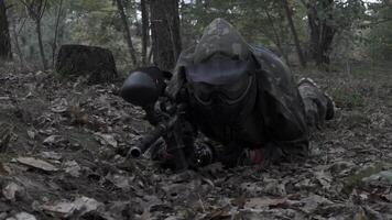 Paintball player crawling on plastunno slow-motion shooting video