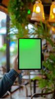 Tablet with green screen in woman hand. Blurred background. photo