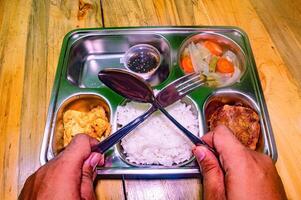 A nutritious school lunch tray with rice, vegetables, fried egg, and a meat patty, promoting healthy eating for children photo