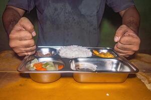 A stainless steel lunch tray containing a balanced meal of rice, vegetables, and protein. This image showcases a nutritious and healthy free lunch concept photo