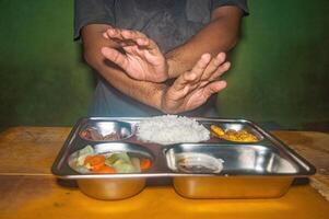 A person is refusing a meal consisting of rice, vegetables, and meat on a metal tray, highlighting the concept of free or nutritious and healthy lunch photo