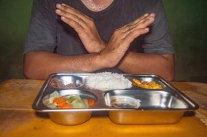 A person is refusing a meal on a tray containing rice, vegetables, and meat. This image represents the concept of free lunch or healthy and nutritious eating photo