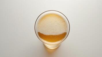 Top view of a glass of frothy golden beer on a light background.Top view of a glass of frothy golden beer on a light background. photo