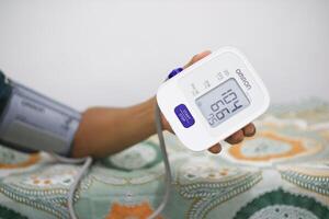 Lampung Selatan, september 13, 2024, A person using a blood pressure monitor at home photo