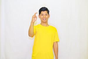 A cheerful man with braces in a vibrant yellow t-shirt demonstrates a small size or just a little gesture against a plain background, suggesting something is tiny or insignificant, photo