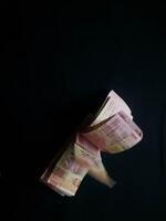 Indonesian Rupiah bills falling in dynamic motion against a dark backdrop photo