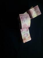 Stack of Indonesian Rupiah currency notes on a dark surface in a still life composition photo
