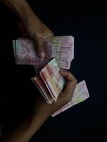 Indonesian Rupiah banknotes neatly stacked on a black background photo
