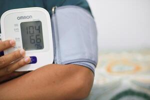 Lampung Selatan, september 13, 2024, Person using digital blood pressure monitor for health check photo