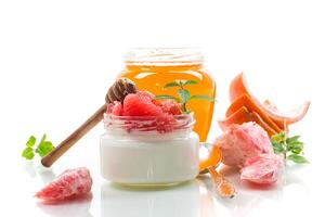 Diet recipe,homemade sweet yogurt in a glass jar with pieces of red ripe grapefruit and honey, isolated on white background photo