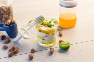Breakfast,homemade yogurt with kiwi, honey and nuts in a glass on a wooden table photo