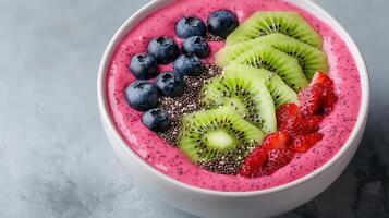 Smoothie bowl topped with sliced kiwi, blueberries, and chia seeds for a colorful, healthy treat. photo