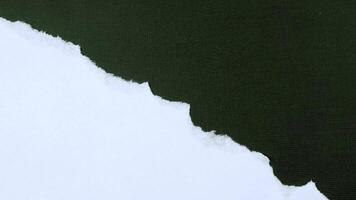 Motion Graphic Torn Paper Edge A dramatic, abstract close-up of a torn piece of paper, revealing a stark contrast of white and dark green. The jagged edge evokes a sense of raw energy and vulnerabili video