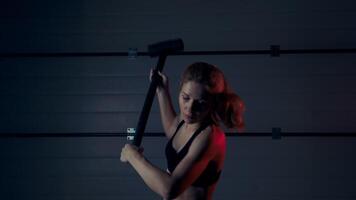 Female athlete with fast and strong blows beats a hammer on a rubber tire performing crossfit exercises video