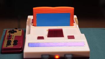 Retro game console with cartridge and controllers displaying loading screen video