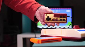 Man holding retro game controller playing on a vintage console video