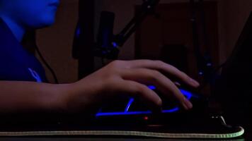 a Rapazes mão usa uma computador rato com néon iluminação, inferior visualizar, sentado dentro uma Sombrio quarto video