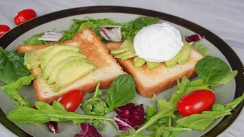 Healthy avocado toast with poached egg and fresh greens on rustic plate video
