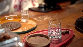 Hands preparing coffee setup with elegant glassware and accessories on wooden counter, showcasing ritual of coffee preparation, focus on detail and artisanal touch in cozy cafe atmosphere. video
