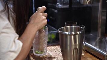 Mixologist preparing fresh cocktail by muddling ingredients mint and lemon in glass, creating vibrant beverage, capturing essence of craftsmanship, refreshing moment of bartending artistry video