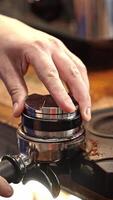 Barista pressing coffee grounds, preparing espresso, hands focused on creating perfect brew, precision of actions symbolizing craftsmanship and quality, art of coffee-making in action, vertical . video