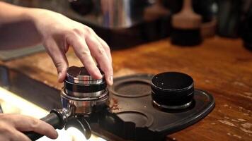 Barista pressing ground coffee with precision and care, preparing espresso with focus on craftsmanship, symbolizing dedication, attention to detail, and art of coffee-making in a cozy cafe ambiance. video