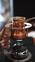 Copper coffee pot on gas burner, symbolizing tradition and evoking essence of Turkish coffee preparation. Hand-held brewing process captures art of slow, mindful coffee-making in intimate setting video