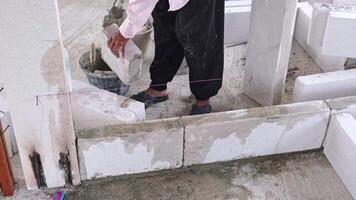 An experienced older female worker building wall using lightweight bricks with cement binding agent ensure a strong secure hold. arranging bricks carefully to meet construction standards for building video