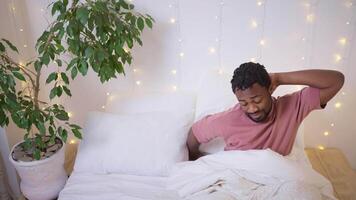 single african man is waking up in his bedroom at home in morning, stretching muscles after sleep video