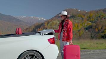 go on a trip by car, young woman opening trunk of cabriolet for loading suitcase, travel alone video