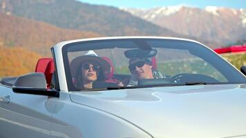 people travelling by car in mountains, sitting in cabriolet and using map in tablet, weekend trip video
