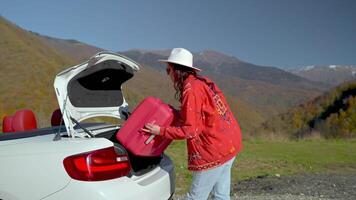 girl tourist loading red suitcase in trunk of convertible car before travelling by auto video