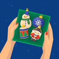 illustration of a hand holding a box with Christmas ornaments snowman, nutcracker, drum, ball. vector