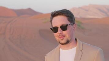 Portrait smiling businessman in sunglasses enjoying sunset in red desert in UAE. video