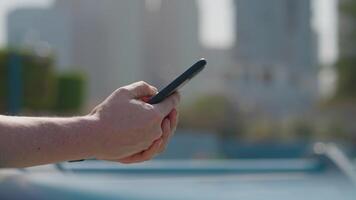 Phone in man's hands browsing in internet swiping pages on cityscape background. video