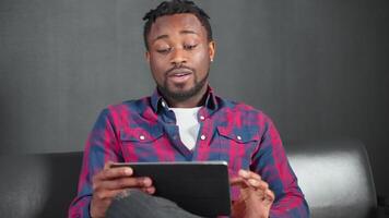 Positive smiling man watching social media in tablet and talking with himself. video