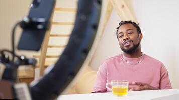 Sociable positive guy creating content using smartphone and ring lamp. video