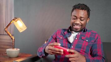 joyful african american gamer playing smartphone games in mobile application, portrait of black guy video