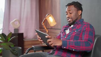 portrait of excited gamer playing game in tablet, joyful african man with modern gadget video