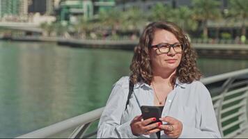 Woman finding destination using navigation map in phone walking on waterfront. video