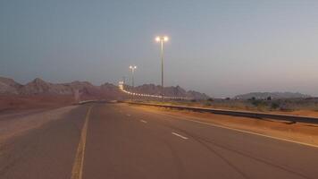Modern illuminated empty highway in red desert on sand mountain background. video
