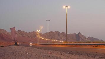 travelling by auto across desert, modern highway along mountains, illuminating lights in evening video