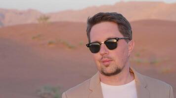 Dreamy pensive businessman in sunglasses enjoying red desert in UAE. video