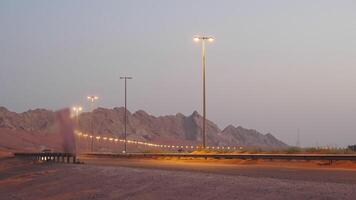 Modern illuminated highway with car in desert on sand mountain background. video